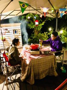 Due persone sedute a un tavolo sotto una tenda di ガーデンハウス Mako Land a Toyama