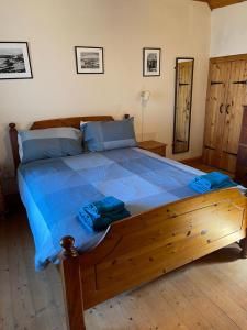 a large wooden bed with blue sheets in a bedroom at The Old Ferryhouse in Port Appin