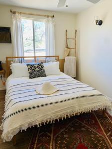 a bed with a hat sitting on top of it at Casa Agave: Comfy Joshua Tree Cottage With Free Breakfast Bar in Joshua Tree