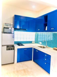 a blue kitchen with white appliances and blue tiles at Ocean Star Apartment Sanur in Sanur