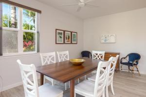 a dining room with a wooden table and white chairs at Waikoloa Colony Villas #2105 in Waikoloa