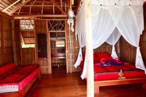 a bedroom with two beds with red sheets and white curtains at TABARI DIVE LODGE in Pulau Mansuar