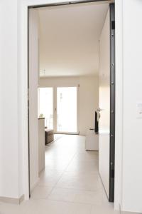Brand New Apartmentcecilia Residence Apt N5 في اجنو: ممر مفتوح مع جدران بيضاء وباب جرار