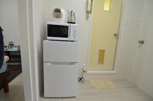eine Mikrowelle auf einem weißen Kühlschrank in der Unterkunft Amont Nakamura - Vacation STAY 83274 in Miyazaki