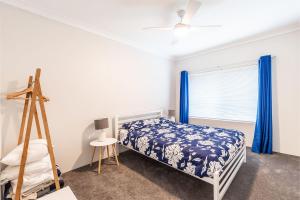 a bedroom with a bed and a window with blue curtains at 4 'Adriana', 83 Ronald Avenue - open plan living with backyard in Shoal Bay