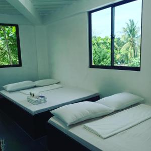 three beds in a room with two windows at Ludy's 2 Pension House in Carles