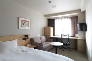 a hotel room with a bed and a desk and a chair at Rhino Hotel Kyoto in Kyoto