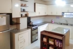 a kitchen with white cabinets and a stove top oven at Skyleigh Apartelle by RedDoorz in Iloilo City