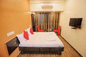 Habitación con cama con almohadas rojas y TV. en Hotel Sai Niwas en Lonavala