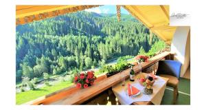 uma varanda com uma mesa e vista para uma floresta em Heimat Apartments - Zillertal em Gerlos