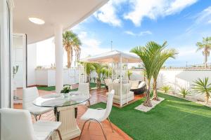 un patio con tavolo, sedie e palme di Apartment Andrea ad Adeje