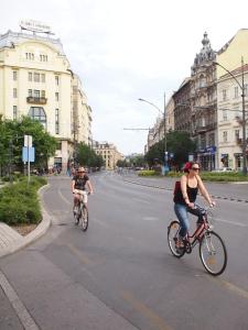 a woman riding a bike down a street next to tall buildings at Budapest Suites in Budapest