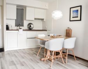 een keuken met een houten tafel en witte stoelen bij Wyn 72 in Hollum