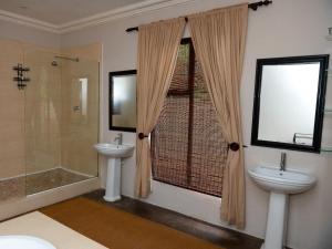 a bathroom with two sinks and a shower and a window at Umdlalo Lodge in Port Shepstone