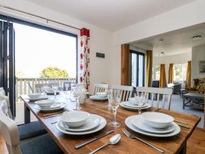 a dining room with a wooden table with plates and silverware at Dovefields in Helston