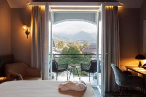 ein Hotelzimmer mit einem Bett und Blick auf einen Balkon in der Unterkunft ERIKA Boutiquehotel Kitzbühel in Kitzbühel