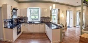 a kitchen with white cabinets and black counter tops at Owls Nest in Edinbane