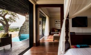 
a room with a bed, chair and a window at Four Seasons Safari Lodge Serengeti in Banagi
