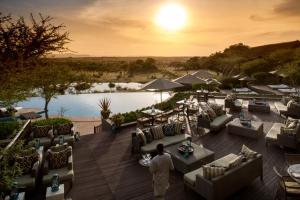 een man staat op een dek met banken en tafels bij Four Seasons Safari Lodge Serengeti in Banagi