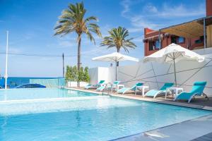 a swimming pool with chairs and umbrellas at Hotel Sol de Jávea in Jávea