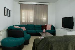 a living room with a blue couch and a tv at MAMA'S FLAT - ΤΟ ΔΙΑΜΕΡΙΣΜΑ ΤΗΣ ΜΑΜΑΣ in Strovolos