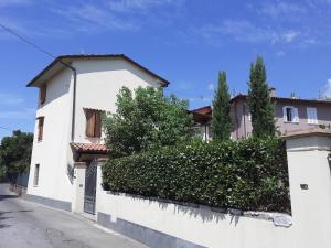 uma casa branca com uma sebe em frente a uma rua em Rustico degli Ulivi em Vallecchia