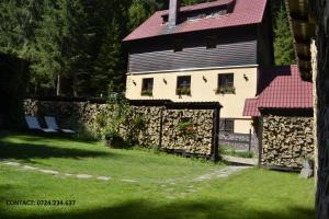 ein Haus mit einem roten Dach und einer Steinmauer in der Unterkunft Casa "Cabana Varciorog Arieseni" in Arieşeni