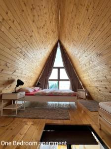 Ce lit se trouve dans une chambre en bois dotée d'une grande fenêtre. dans l'établissement Lazar&Mila Apartments, à Žabljak