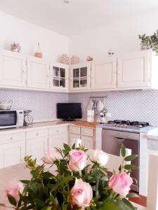 uma cozinha com armários brancos e rosas cor-de-rosa numa mesa em Rustico degli Ulivi em Vallecchia