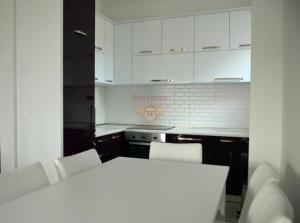 a kitchen with white cabinets and a white table and chairs at Apartman Pejovic in Petrovac na Moru