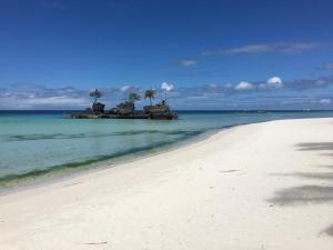 een strand met palmbomen op een eiland in de oceaan bij Swahili Apartelle in Boracay