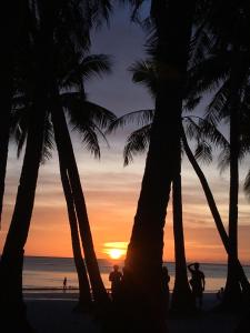 puesta de sol en la playa con palmeras en Swahili Apartelle, en Boracay