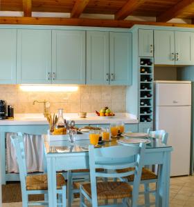 a kitchen with blue cabinets and a table with chairs at Myrtillo I Luxury Traditional House in Spanokhórion