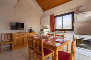 a kitchen with a wooden table and a dining room at Le Bleuet du Lac in Savines