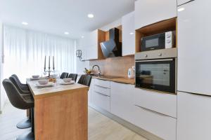 uma cozinha com armários brancos e uma mesa com um micro-ondas em Zara Lumina Apartment em Zadar