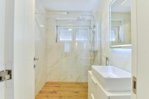 een witte badkamer met een wastafel en een douche bij Zara Lumina Apartment in Zadar