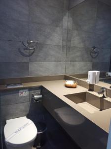 ein Badezimmer mit einem WC und einem Waschbecken mit einem Spiegel in der Unterkunft Dionysos Central in Paphos City