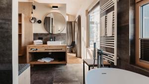 a bathroom with a tub and a sink and a mirror at Hofgut Wagrain Apartment & Lifestyle Resort in Wagrain