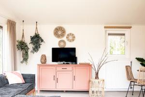 a living room with a tv on a cabinet at StayatSas Tiny House Sam in de bossen op de Veluwe! in Epe
