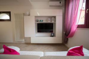 a living room with two white beds and a television at La Casetta di Chiara B&B in Polignano a Mare