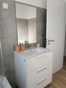 a bathroom with a white sink and a mirror at Apartamento Vilamar in Vila Nova de Milfontes