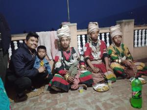 un grupo de personas sentadas en un balcón con comida en Laxmi Homestay with main square view, en Bhaktapur