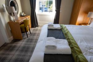 two beds in a hotel room with towels on them at The Waverley Hotel in Callander