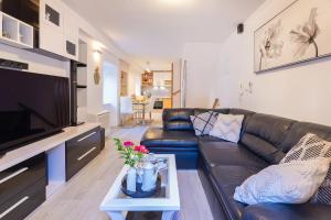 a living room with a leather couch and a tv at Domino Holiday Home in Dubrovnik