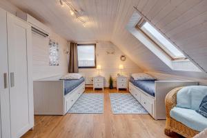 a attic bedroom with two beds and a window at Dom Wakacyjny Baltic Home & Dom Baltic Home Garden Inn in Zastań +50 photos