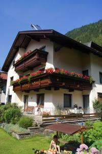 a woman sitting under an umbrella in front of a building at Haus Josef in Mayrhofen