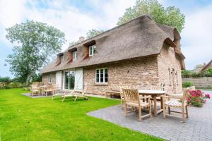 a house with a thatched roof with tables and chairs at Haus Eva Marie in Oldsum