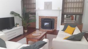 uma sala de estar com mobiliário branco e uma lareira em Gîte Maison des Poules em Marvejols