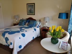 Un dormitorio con una cama y una mesa con un jarrón de flores en Cúl Draíochta B&B en Cahersiveen