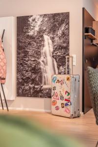 a suitcase sitting next to a painting of a waterfall at FOREST Private Suites in Titisee-Neustadt